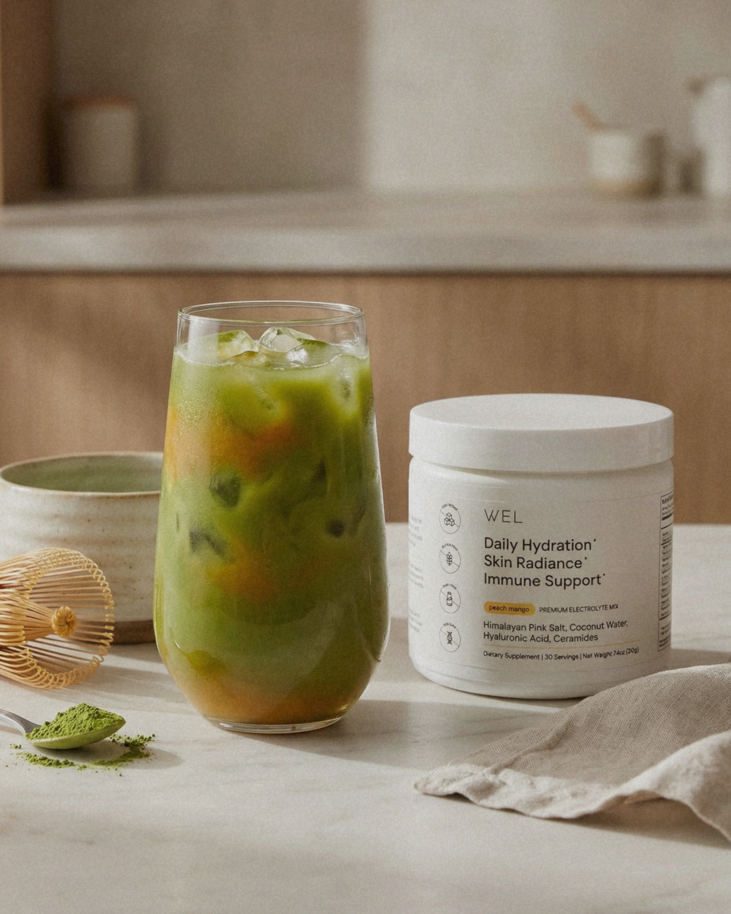 Glass of iced peach mango matcha drink made with WEL premium electrolytes.