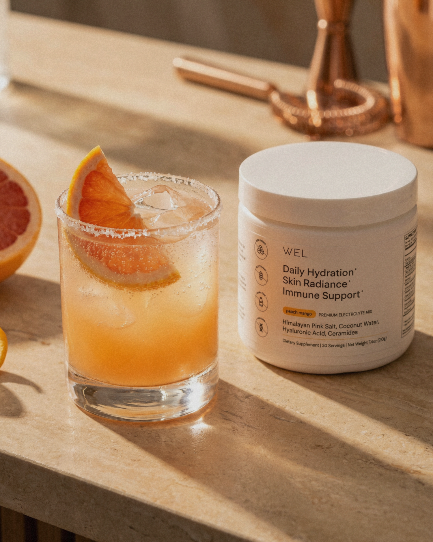 Glass of peach mango paloma with a slice of grapefruit made from WEL premium electrolytes.